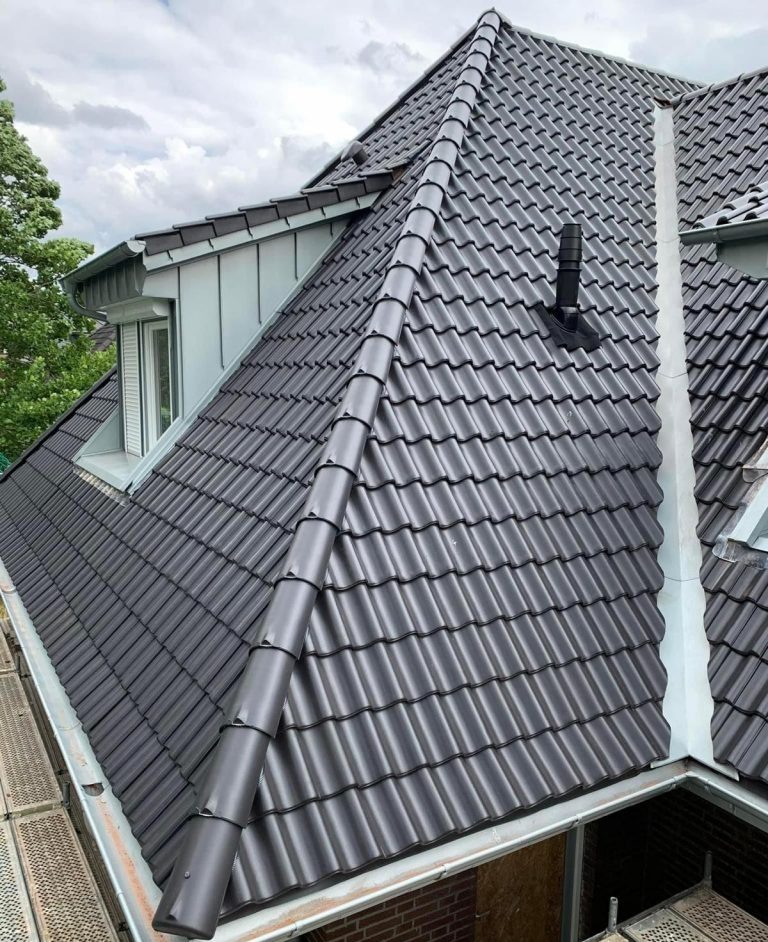 Dach dwuspadowy z czerwonej dachówki podczas prac dekarskich